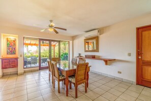 A dining area with a glass-top table, wicker chairs, a ceiling fan, and a view of greenery outside. - 2-Unit Bundle: Bahia Pez Vela Resort Villas (Playa Ocotal)