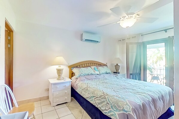 Ein Schlafzimmer mit Bett, Nachttischlampen, Deckenventilator und Klimaanlage.