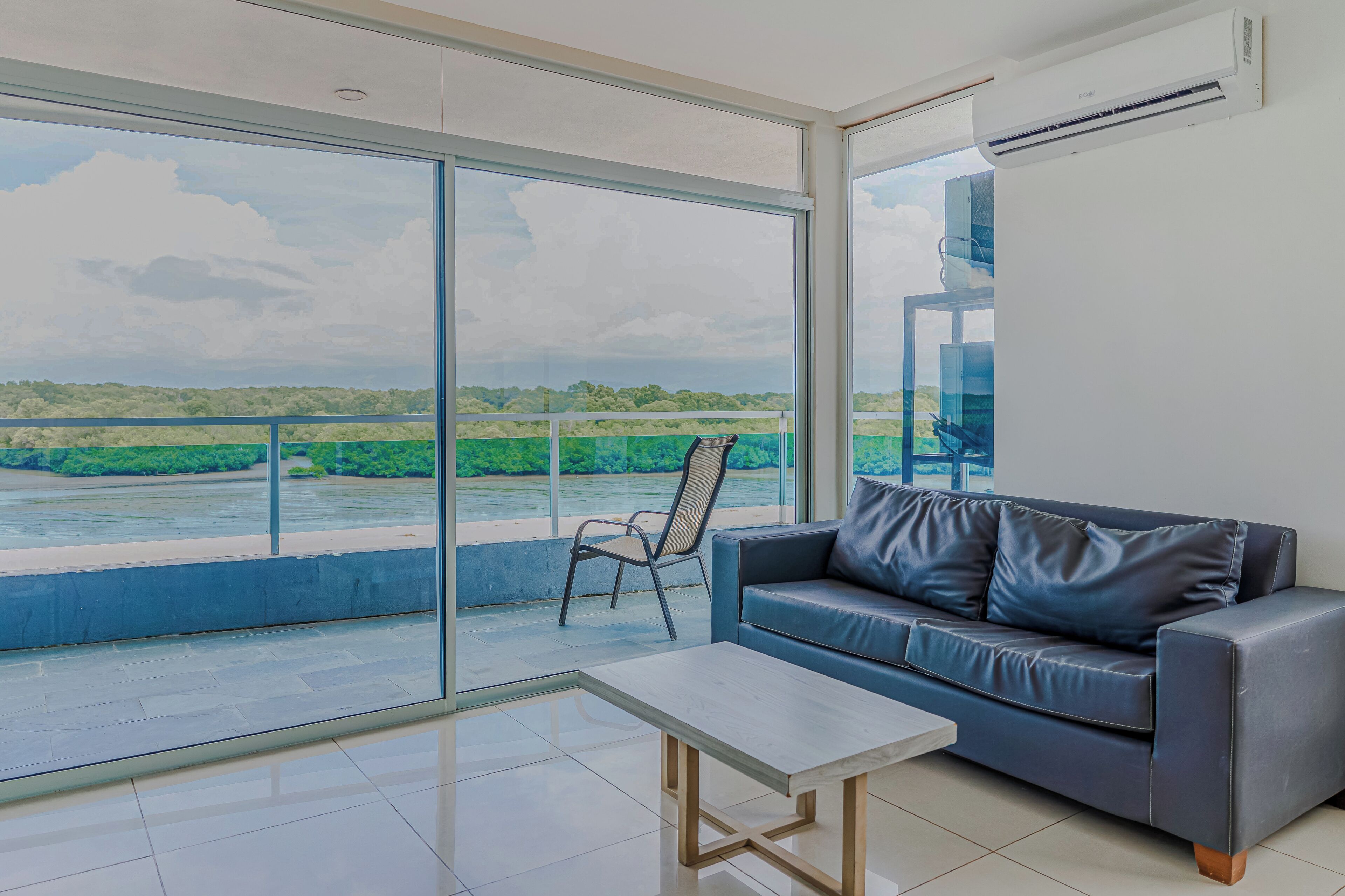 A modern living room with a sofa, a chair, and a table, overlooking a river.