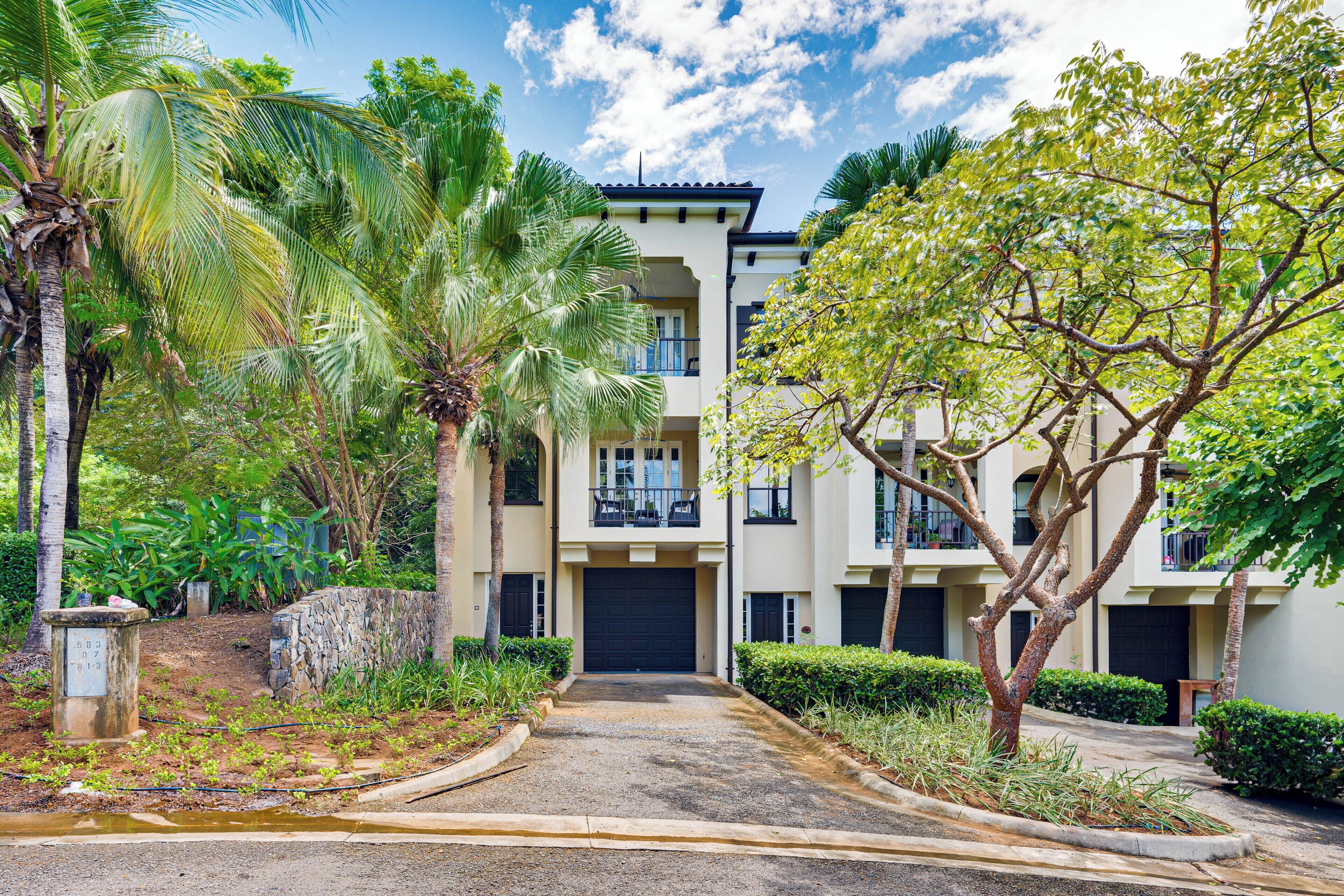 A multi-story residential building with a paved driveway leading to a gated entrance.