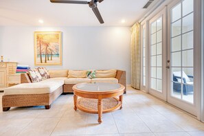 A spacious living room with a large sectional sofa, a round coffee table, and a ceiling fan.