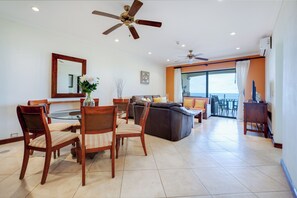 A spacious living area with a dining table, chairs, a sofa, and a ceiling fan.