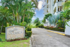 A residential area with a sign reading 'CONDOMINIOS OCEANICA' and a clear sky.