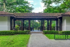 A covered outdoor seating area with a tiled roof, surrounded by greenery and a paved walkway. - Tamarindo Villa w/ Private Pool, Beach Club Access (Tamarindo)