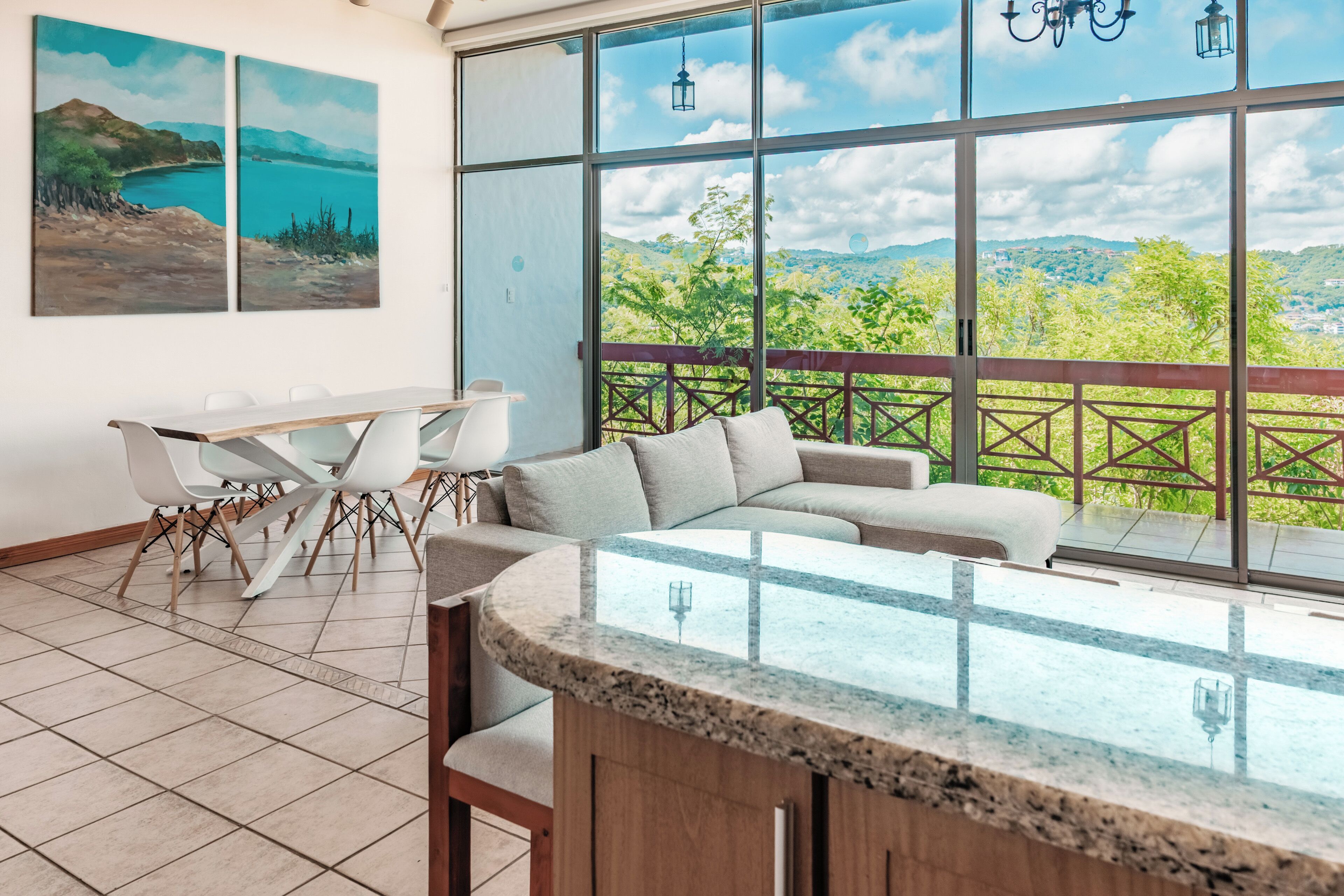 A modern room with a large window, a dining area, and a seating area with a view of the landscape.