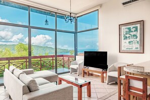 A spacious balcony with a large window offering a scenic view of hills and a body of water. - Playa del Coco 3BR: Ocean Views & Pools! (Playa Hermosa)