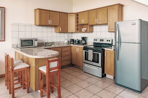 A compact kitchen with wooden cabinets, a microwave, a stove, and a refrigerator.