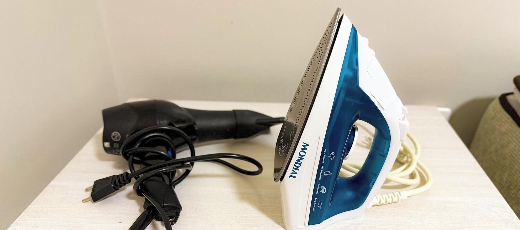 A white and blue iron with a cord, placed on a wooden surface.