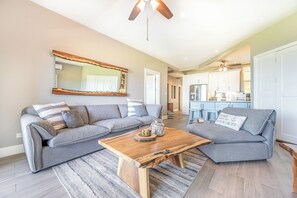 A modern living room with a sectional sofa, a wooden coffee table, and a large mirror.