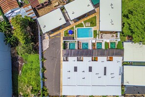 An aerial view of a property with multiple buildings, a swimming pool, and surrounding greenery. - Walk to Del Coco Beach & Restaurants: 2 Condos! (Playas del Coco)