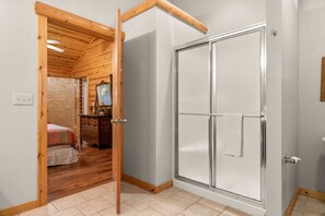 A room with a wooden ceiling, a sliding glass door, a bed with a patterned bedspread, and a dresser with a mirror. - Luxury in the Ozarks-Four  Master Bedroom Suites, Sleeps 14, Lots of Space for the Whole Family!-20 (Branson)