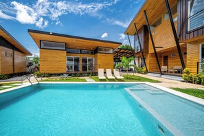 A modern building with a swimming pool, wooden exterior, and a covered outdoor seating area. - 'Veranera' Condo w/ Pool Access, 1/2 Mi to Beach! (Playas del Coco)