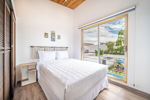 A bedroom with a large bed, a nightstand, a window with a view of the outside, and a ceiling with wooden beams. - 'Veranera' Condo w/ Pool Access, 1/2 Mi to Beach! (Playas del Coco)