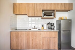 Eine Küche mit Holzschränken, einem Edelstahlkühlschrank, einer Mikrowelle und einer Kaffeemaschine.