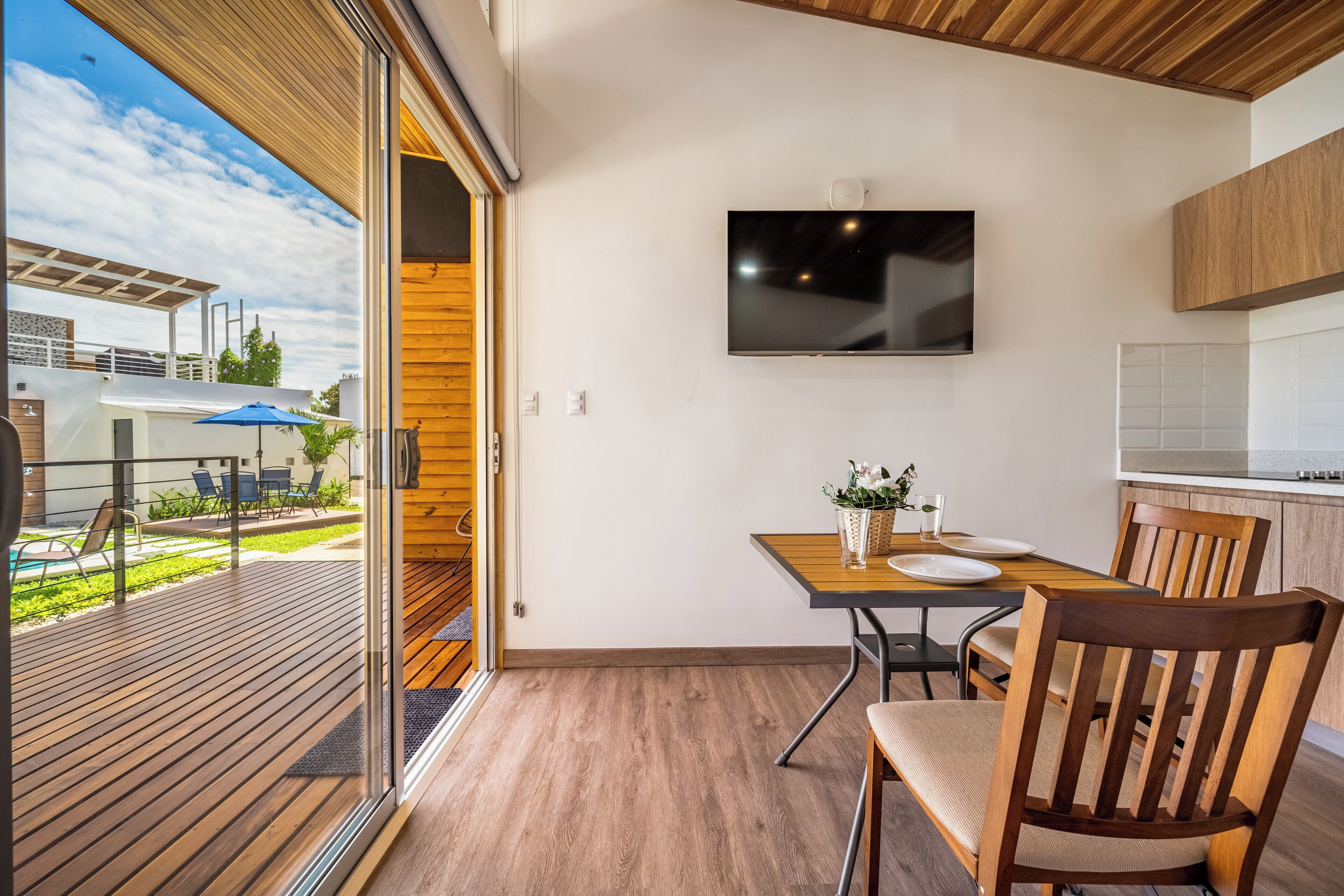 Eine moderne Küche mit Flachbildfernseher, Holzboden und einem Essbereich mit Tisch und Stühlen.