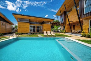 A modern pool area with a clear blue pool, wooden deck, and lounge chairs. - Modern Studio w/ Pool Access Near Playas Del Coco! (Playas del Coco)