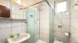 A modern bathroom with a glass shower enclosure, a white sink, and a toilet. - ASA Apto Frente Mar Barra Norte BC (Balneário Camboriú)