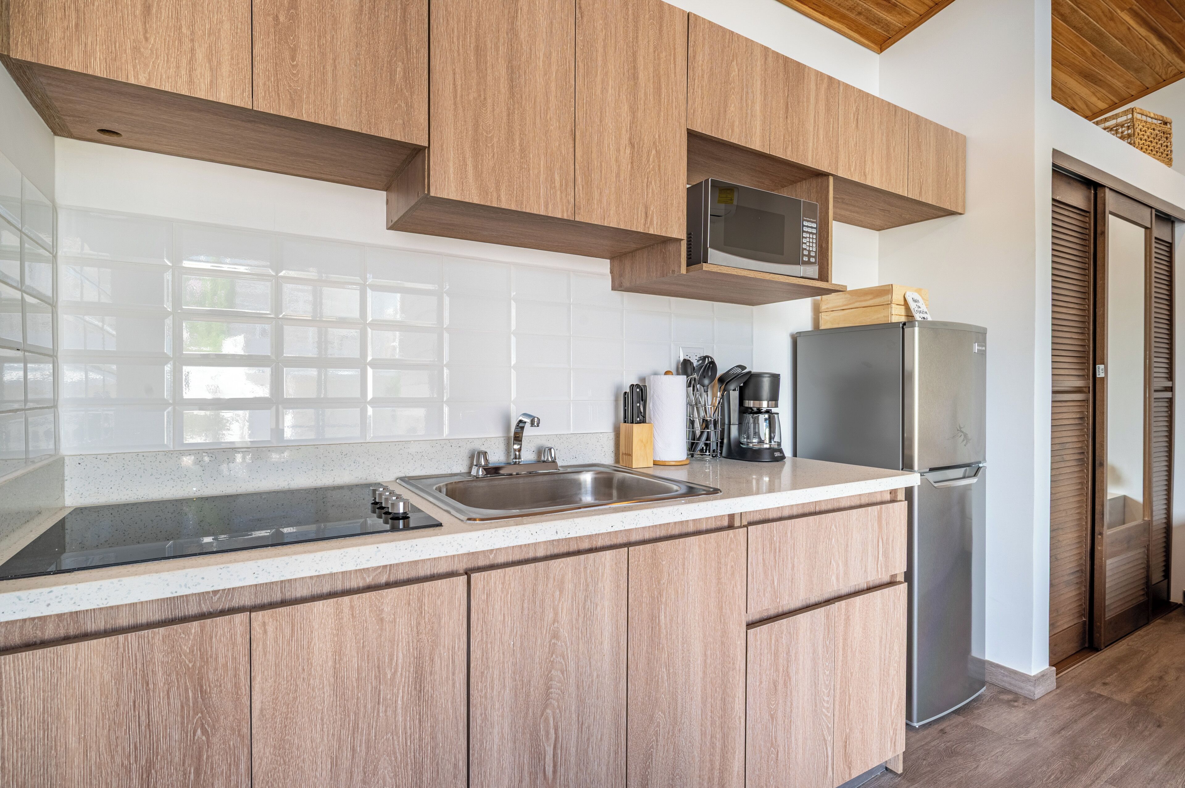 Una cocina moderna con armarios de madera, un lavamanos de acero inoxidable, un microondas y un refrigerador.