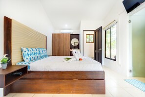 A modern bedroom with a large bed, wooden headboard, and a small bedside table with a plant. - Step-Free Studio w/ Pool Access, Walk to Beach! (Playas del Coco)