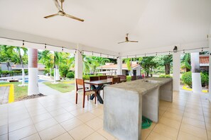 A covered outdoor dining area with a concrete bar, chairs, and ceiling fans. - Step-Free Studio w/ Pool Access, Walk to Beach! (Playas del Coco)