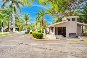 A hotel entrance with a covered seating area, palm trees, and a clear sky. - Step-Free Studio w/ Pool Access, Walk to Beach! (Playas del Coco)