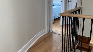 Corredor com piso de madeira que leva a um quarto com uma cama.