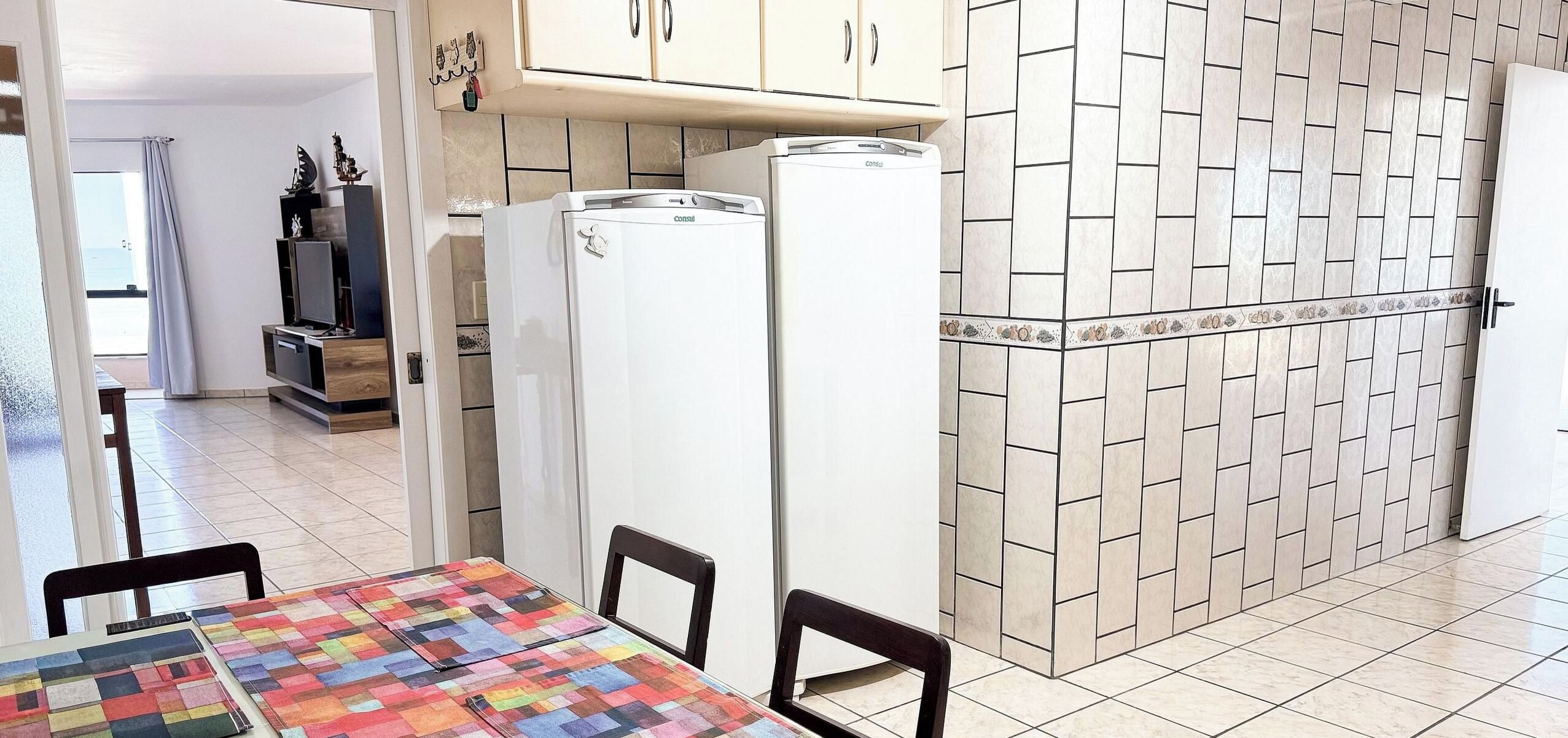 Una cocina con armarios blancos, un refrigerador y un salpicadero de azulejos.