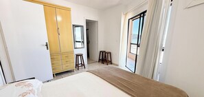Quarto com cama, guarda-roupa, janela e porta.
