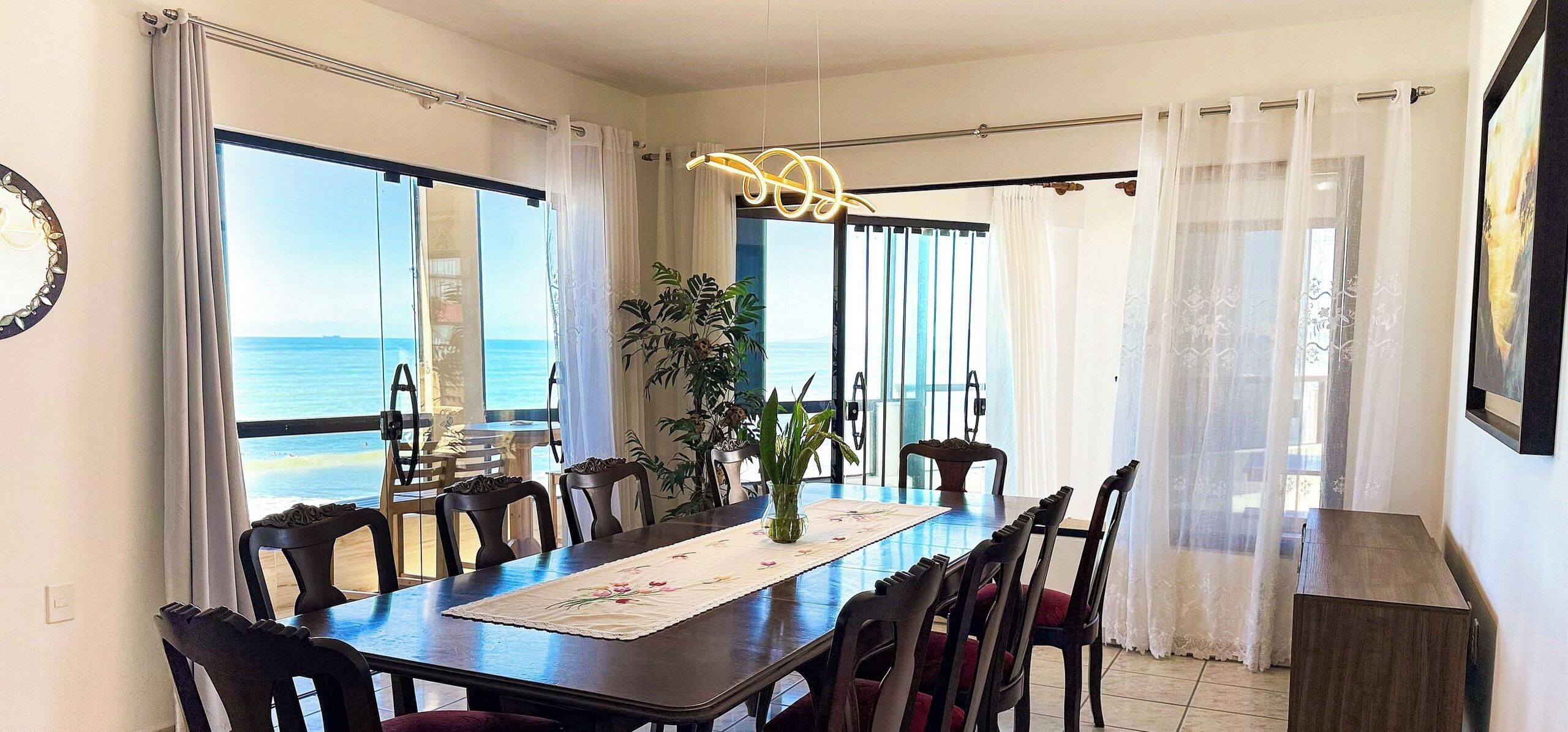 Comedor con vista al mar, una mesa con sillas y un centro de mesa con plantas.