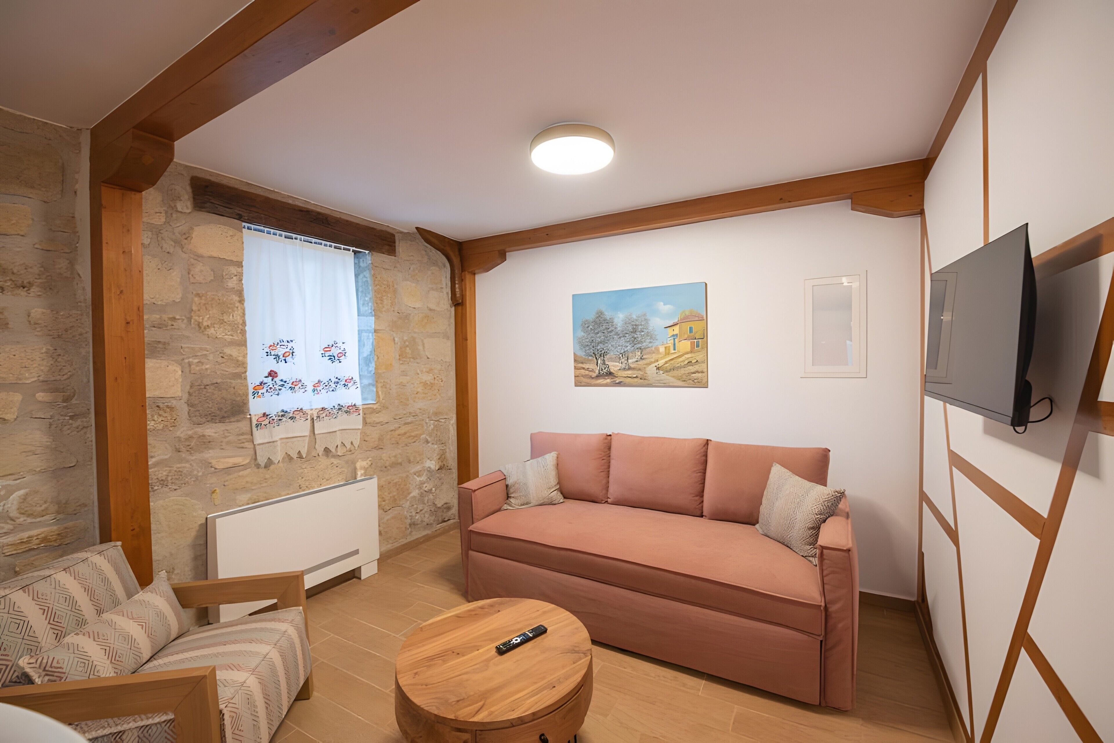 Ein gemütliches Wohnzimmer mit einer Couch, einem Holztisch und einem an der Wand befestigten Fernseher.