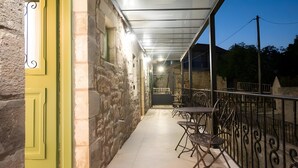 Un patio extérieur abrité, doté de murs en pierre, d’une porte jaune et de mobilier en métal.