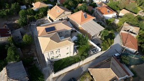 Vue aérienne d’un quartier résidentiel composé de plusieurs maisons, dont certaines ont des toits inclinés et des panneaux solaires, le tout entouré de verdure.