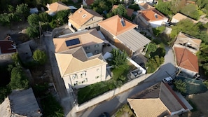 An aerial view of a residential area with multiple houses, some with sloped roofs and solar panels, surrounded by greenery. - Apartment 'Dervisia Stone Houses 3' with Mountain View, Wi-Fi and Air Conditioning (Lazarata)