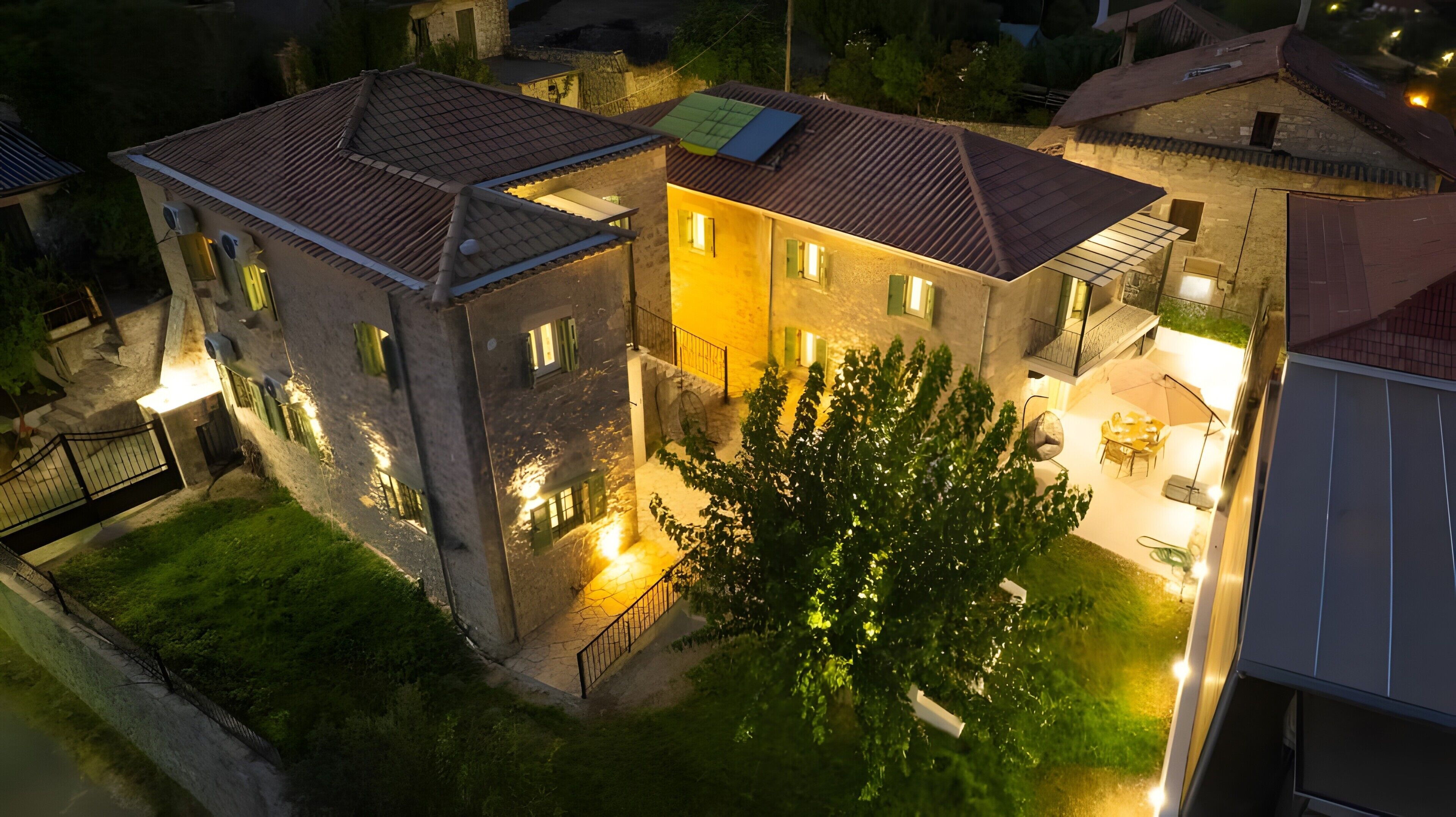 A two-story building with a courtyard, outdoor seating, and a tree.
