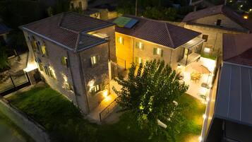 A two-story building with a courtyard, outdoor seating, and a tree.