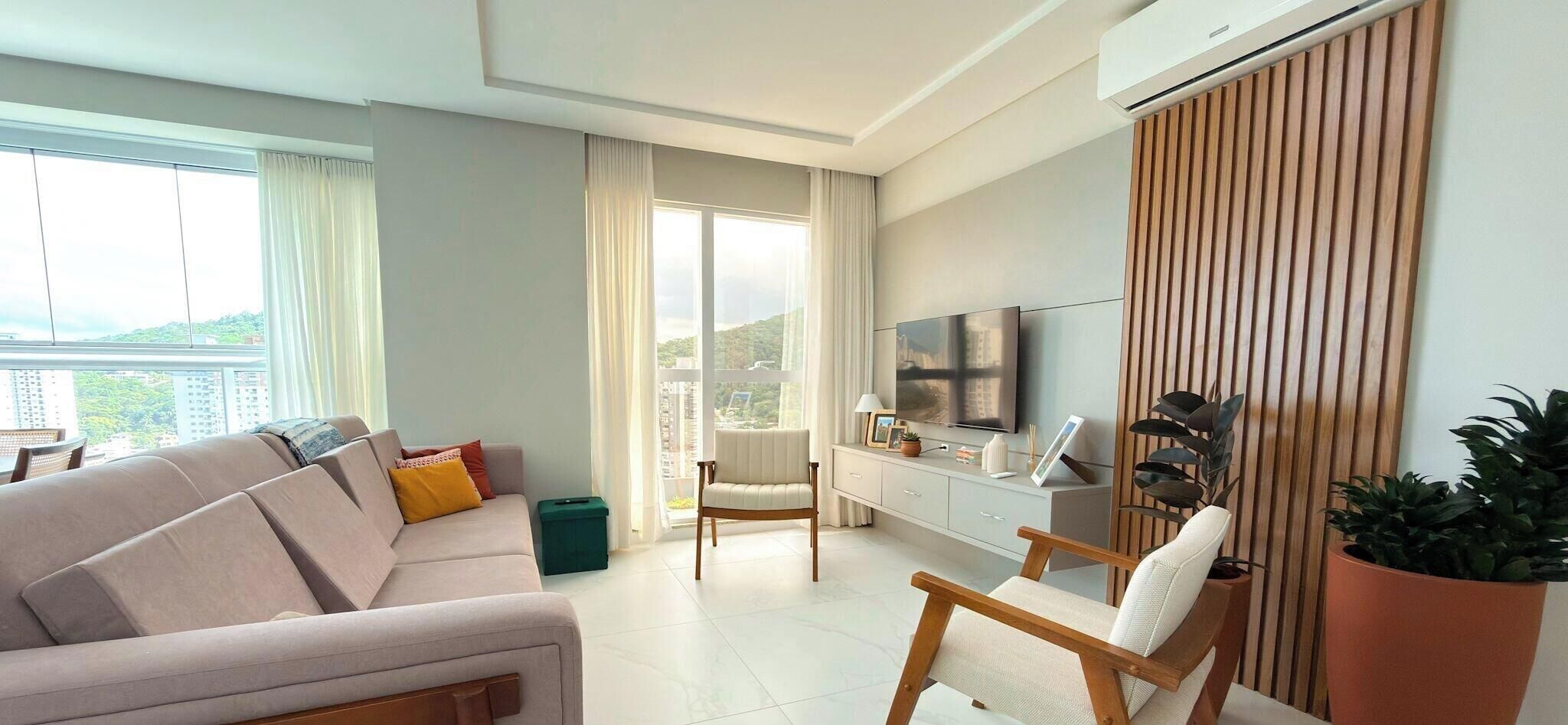 Een moderne woonkamer met een bank, fauteuil en een televisie op een dressoir.