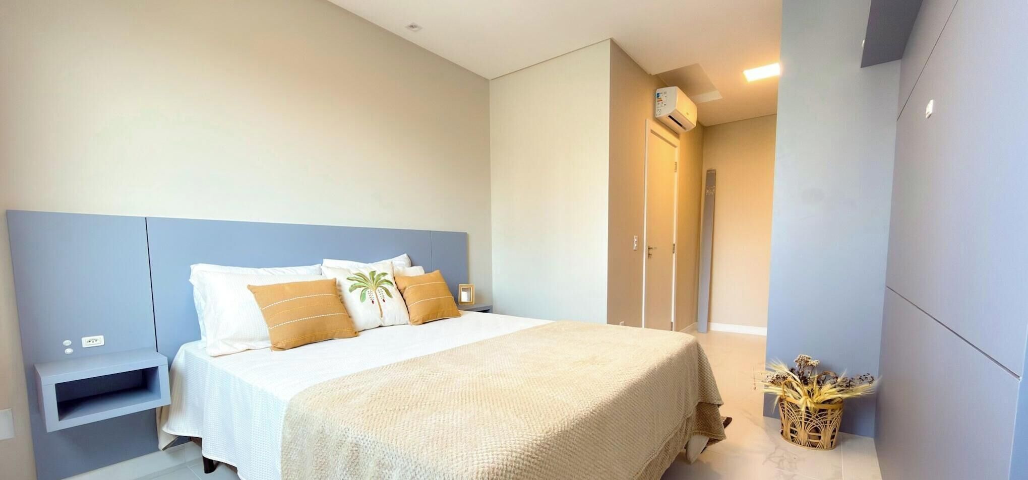 A bedroom with a bed, bedside table, and a wall-mounted air conditioning unit.