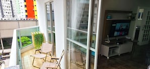 A balcony with a chair, a small table, and a potted plant. - ASA 3QT Leblon Ar Av. Brasil Centro BC (Balneário Camboriú)