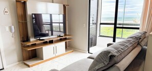 Uma sala de estar moderna com televisão de tela plana, móvel de madeira para TV e um sofá.