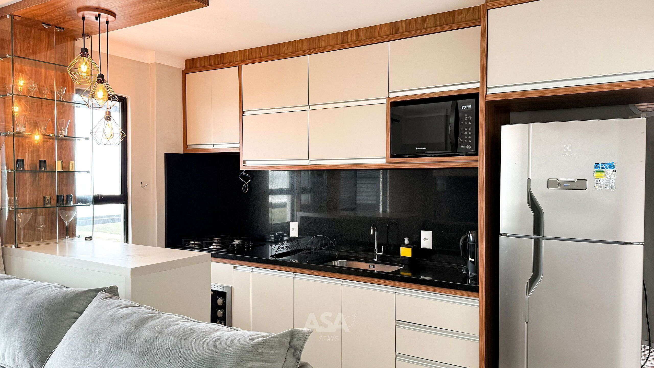Eine moderne Küche mit integriertem Mikrowellenherd, einem Edelstahlkühlschrank und einer schwarzen Arbeitsplatte.