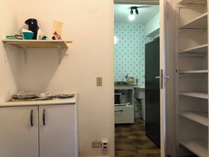 A kitchen with a microwave, a kettle, and a shelf with various items. - Cozy, fully equipped, and quiet outbuilding 300m from USP in Vila Butantã (São Paulo)