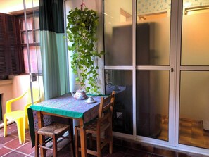 A room with a table set for tea, a chair, a potted plant, and a sliding glass door. - Cozy, fully equipped, and quiet outbuilding 300m from USP in Vila Butantã (São Paulo)