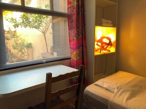 A small room with a window, a bed, a chair, and a wall-mounted lamp. - Cozy, fully equipped, and quiet outbuilding 300m from USP in Vila Butantã (São Paulo)