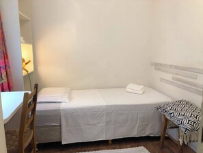A single bed with a white bedspread and a matching pillow, a wooden headboard, a small bedside table, and a patterned throw blanket. - Cozy, fully equipped, and quiet outbuilding 300m from USP in Vila Butantã (São Paulo)