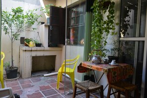 A small patio area with a table, chairs, potted plants, and a window. - Cozy, fully equipped, and quiet outbuilding 300m from USP in Vila Butantã (São Paulo)