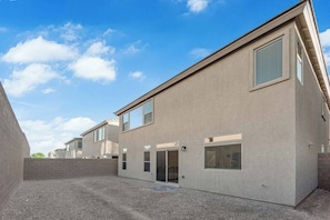 Een modern gebouw met een plat dak, grote ramen en een grindpad.