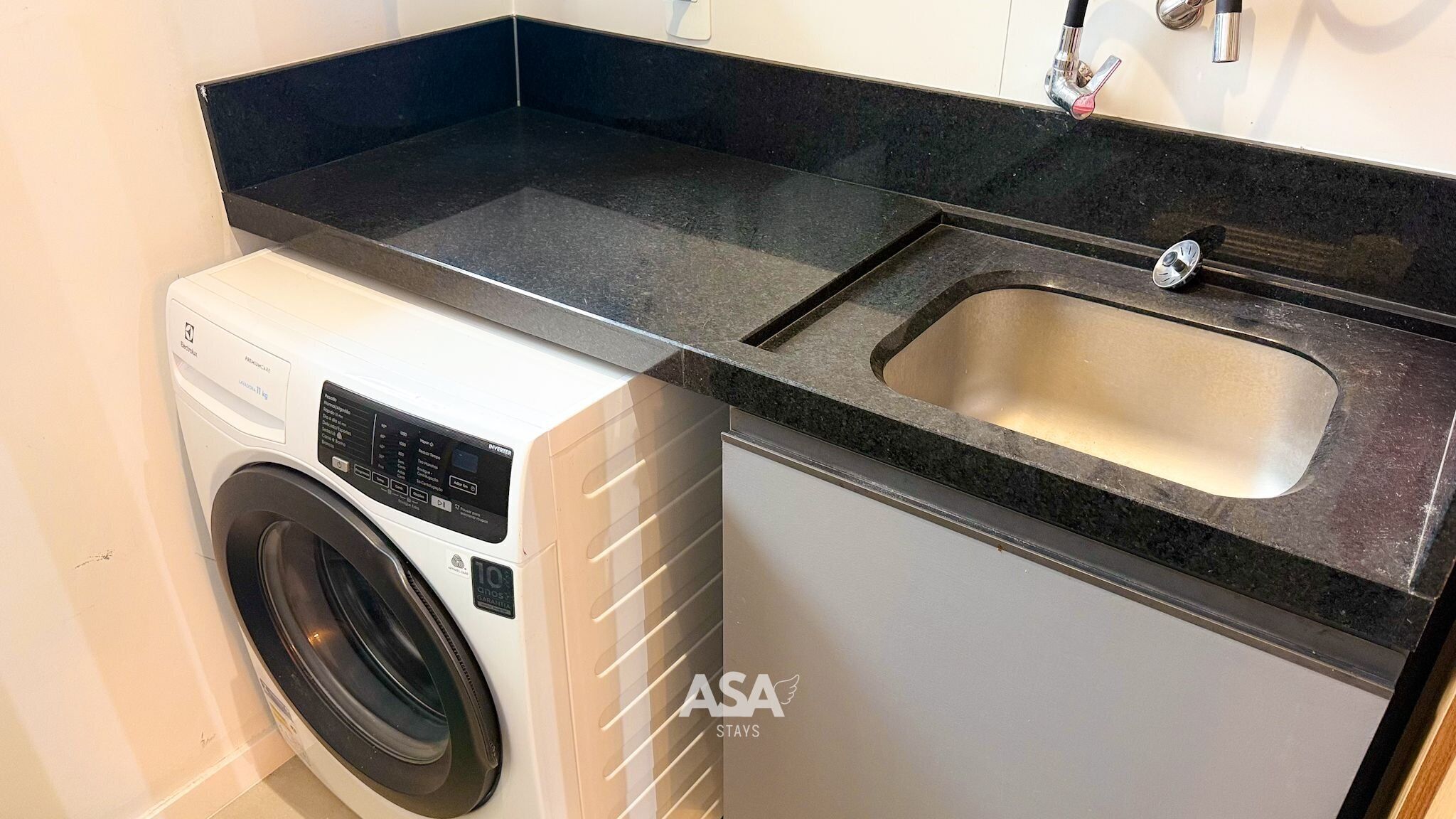 A compact kitchen with a washing machine, a sink, and a countertop.