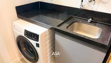A compact kitchen with a washing machine, a sink, and a countertop.