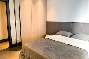 A hotel room with a bed, bedside table, and a wardrobe. - ASA Apto de Alto Padrao Ed a Beira Mar Design (Balneário Camboriú)