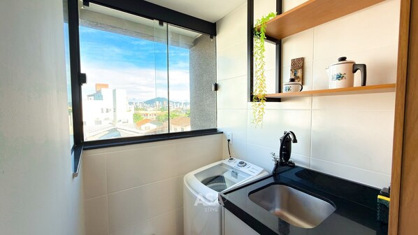 A compact kitchen with a window, a washing machine, and a sink.